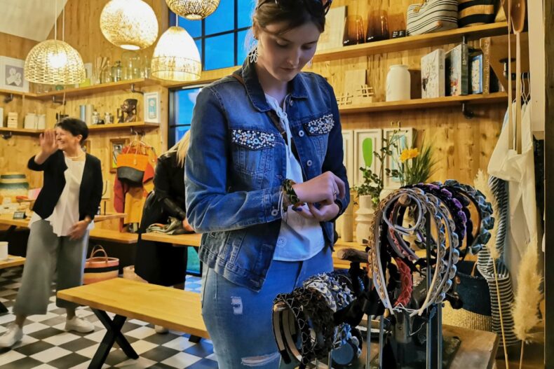 Stilvolle Shopping-Atmosphäre: Besucherinnen stöbern durch handgefertigte Accessoires im charmanten Ladenambiente.
